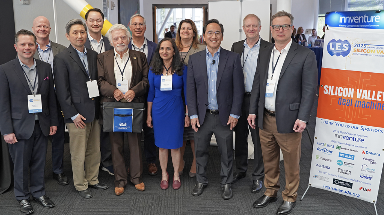 A group photo of attendees from the Silicon Valley Deal Machine event. This event, hosted by the Silicon Valley Chapter, brought together over 110 innovation leaders, IP professionals, and business dealmakers at the Computer History Museum in Mountain View, California. Pictured in the photo are 11 of these attendees next to the poster for the event.